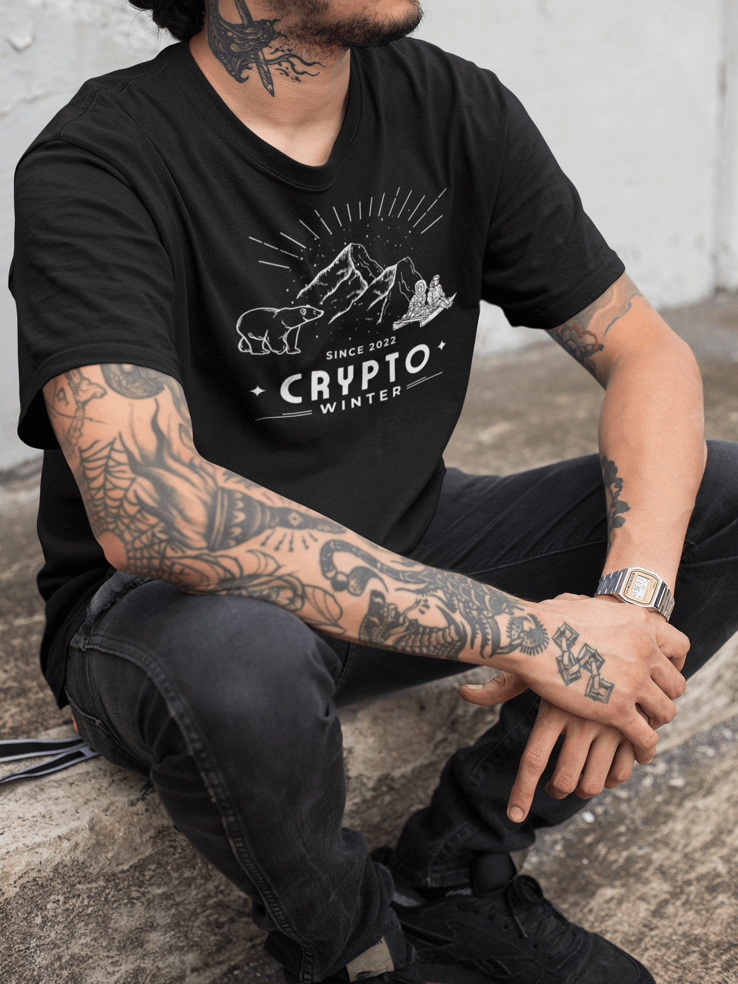Tattooed hispanic man wearing "Crypto Winter' NFT T-shirt sitting on pavement