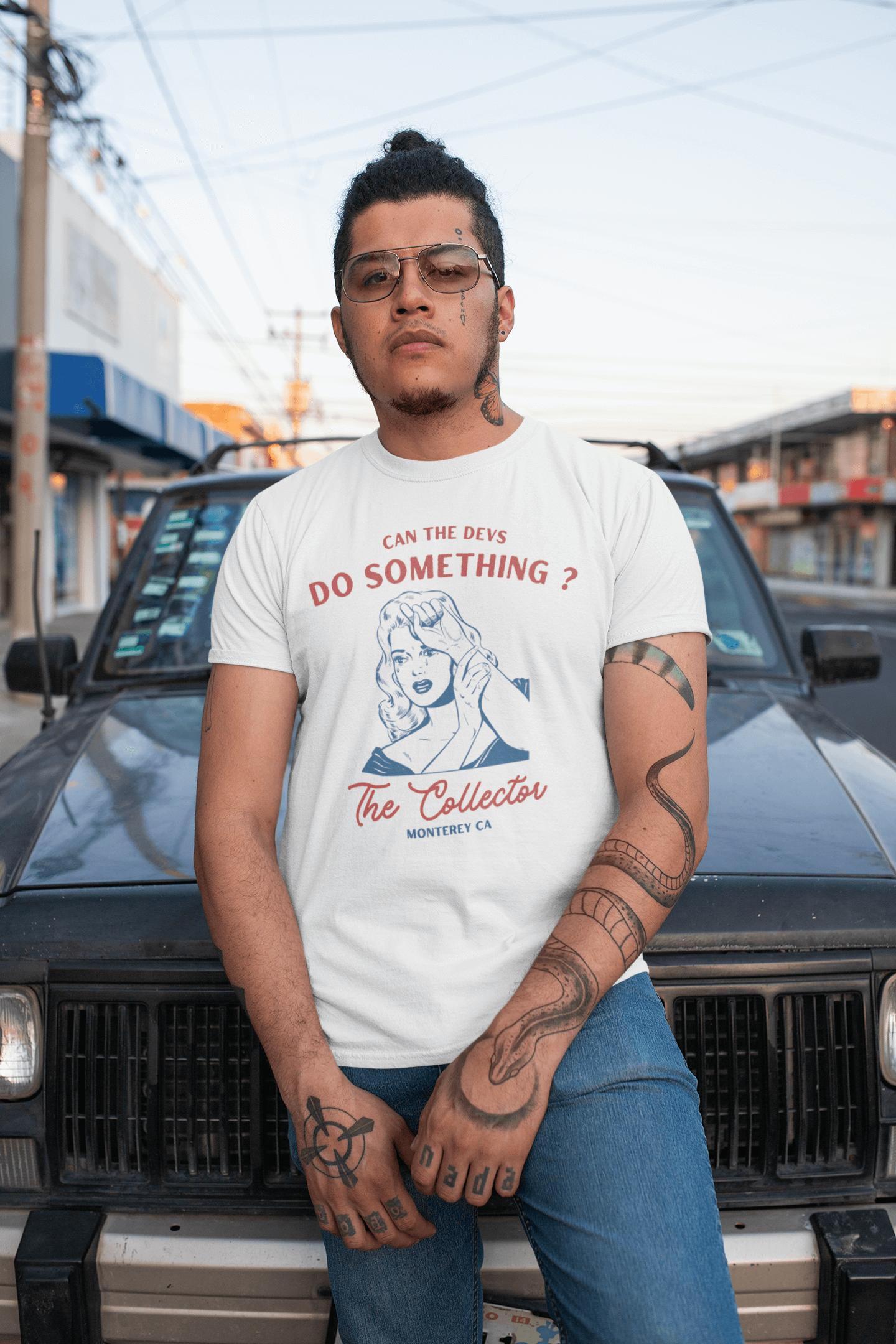 Tattooed man leaning on car wearing "Can the devs do something?" NFT T-shirt